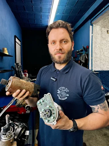Profissional segurando peças automotivas em uma oficina